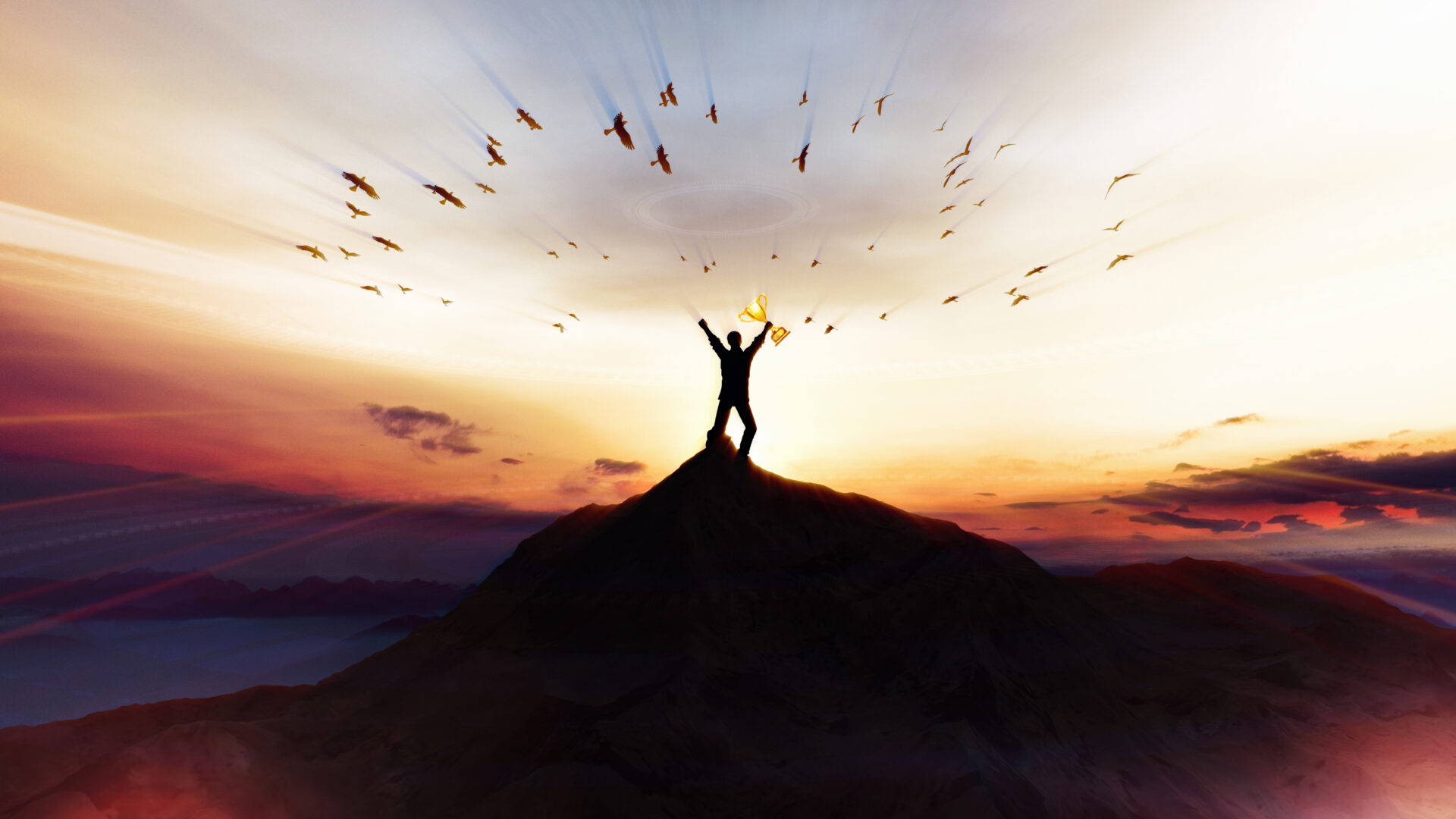 A silhouetted person stands on a mountain peak with arms raised towards a flock of birds, against a vibrant sunset background.